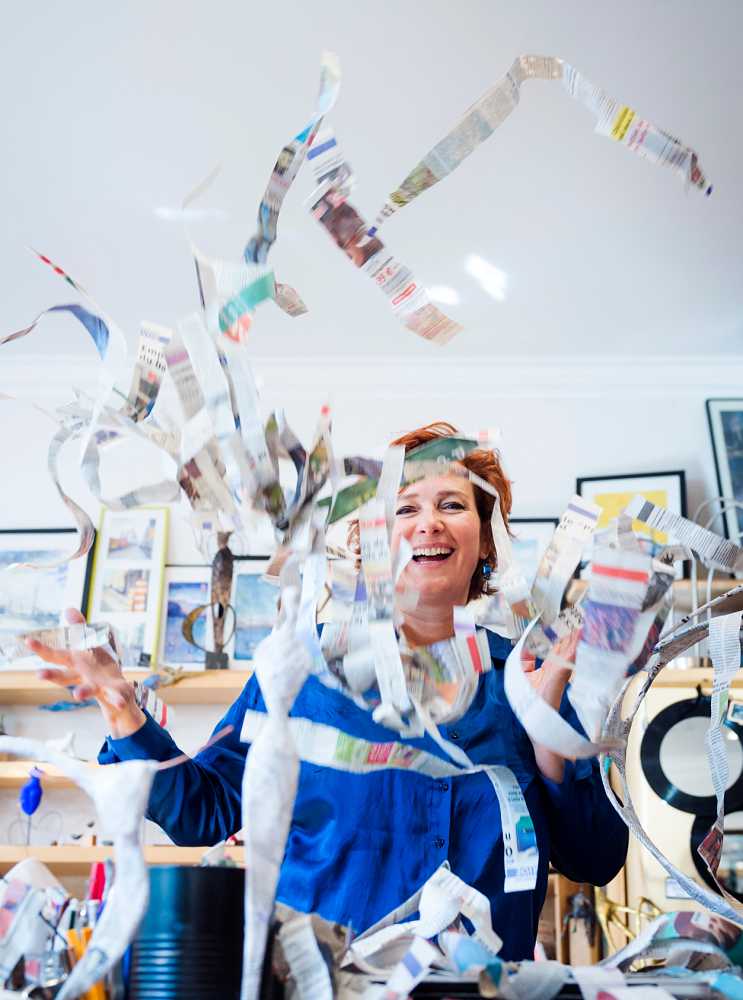 fun relaxed portrait of sculptor throwing newspaper for papier maché in air