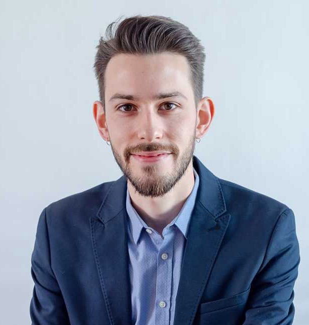 formal professional headshot, bearded young man in dark blue suit