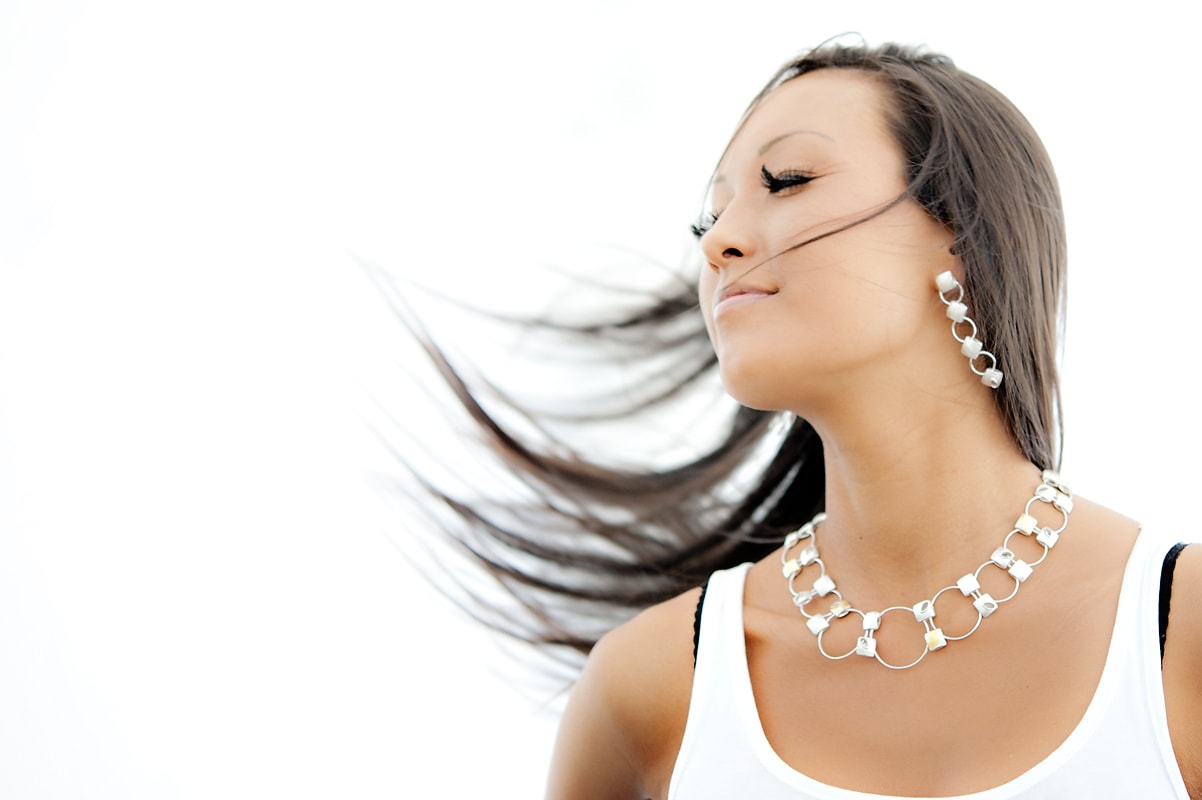 model with silver earrings and statement piece silver necklace swinging hair - movement shot