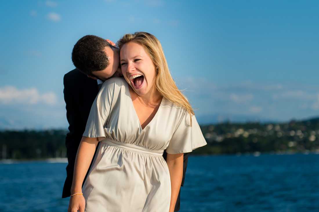 couple laughing on speedboat, man kissing woman's neck