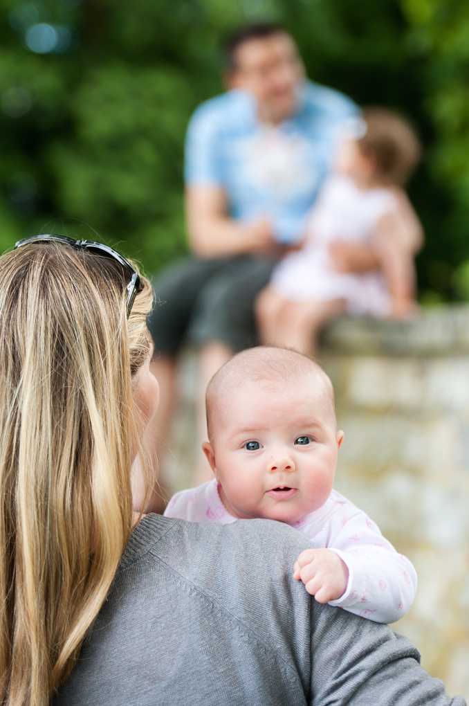 family of four baby looking at camera, mother looking at father and other child in background