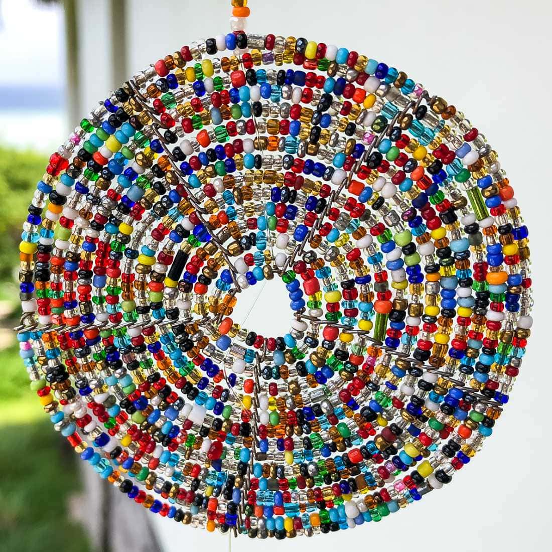 coaster like spiral of tiny colourful glass beads hanging against the light.